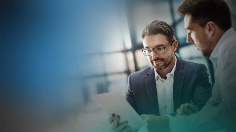 Zwei Männer besprechen sich und halten dabei ein Dokument in der hand