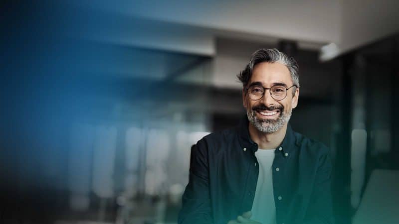 Ein Mann mit Brille und Bart schaut in die Kamera