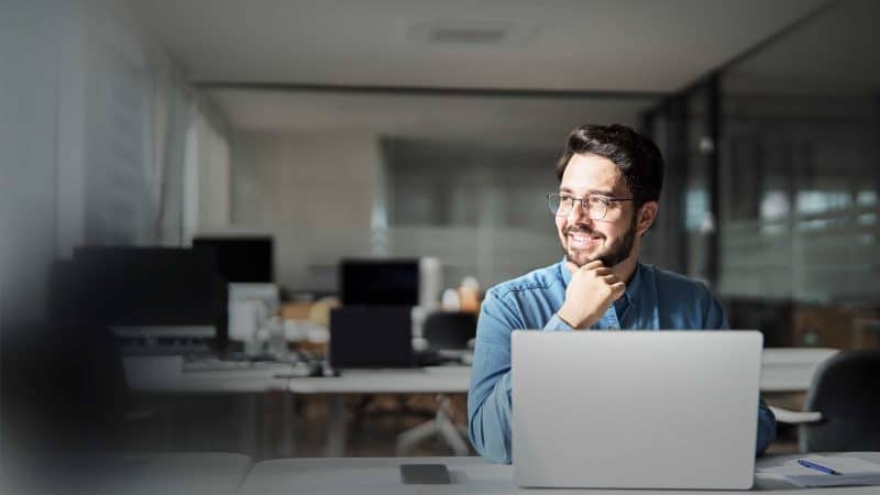 Mann sitzt vor seinem Rechner und und stützt sein Kinn die rechte Hand